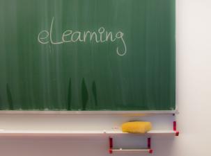 Large green chalkboard on a white wall displaying the word eLearning in white chalk