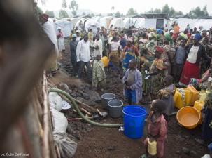 Many people wait for water at the water tank at a refugee camp in the DRC