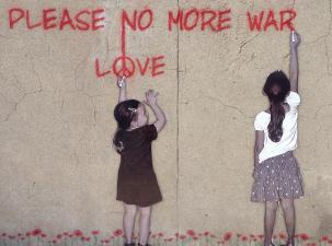 Two young girls making graffiti on a cracked beige wall which says please no more war in red spray paint