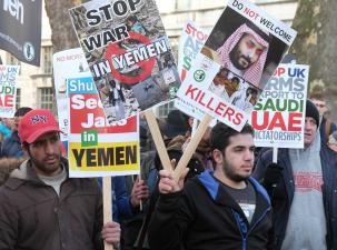 Male protesters looking serious holding wooden placards against the war in Yemen