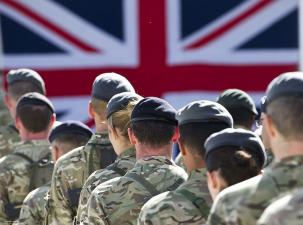 A view of British troops from behind who are standing infront of a British flag