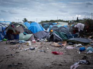 Many broken tents sit with lots of rubbish on the floor infront at a migrant camp in Calais
