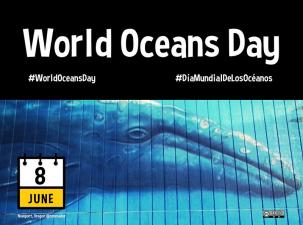 Mural of a whale swiming through the ocean with a black banner above stating World Oceans Day