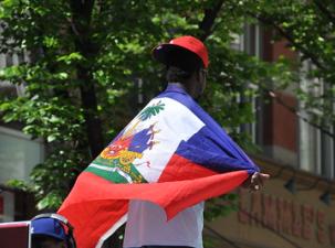 Man on his back with the flag of Haiti on his shoulders.