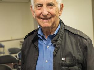 Image of Daniel Ellsberg U.S. whistle-blower. A senior white male smiles warmly into the camera wearing a white shirt and black&nbsp;jacket. 