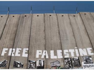 Palestine 2011. Israel's Wall in Bethlehem, West Bank. A large wooden fence with barbed wire on the top has the words 'Free Palestine' written in white paint on it.