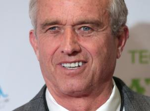 Portrait of Robert F. Kennedy Jr, an older white gentleman with grey hair, he is smiling and wearing a grey suit