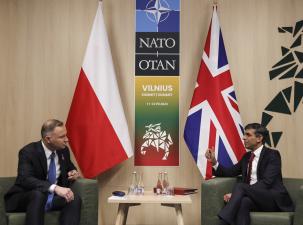 Prime Minister Rishi Sunak meeting with the President of Poland, Andrzej Duda whilst attending the NATO summit in Vilnius. The two men sit infront of their respective country flags, between them on the wall is a poster of the event 