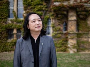 2025 Right Livelihood laureate Audrey Tang stands in a courtyard infront of a beautiful building overgrown with leaves.