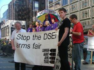 CAAT protesters hold a large white banner which says 'Stop the DSEi arms fair'