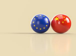 A digital rendering features two glossy spheres, one adorned with the flag of the European Union and the other with the flag of China, set against a plain, light beige background. 