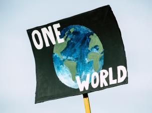 A large sign is painted with the image of the Earth. In white letters it says One World.