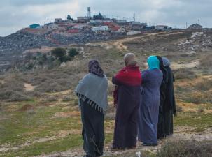 A group of Palestinian women look up at an illegal Israeli outpost in the West Bank village of Jalud. The village has been a frequent target of violence from the settlers surrounding the village.