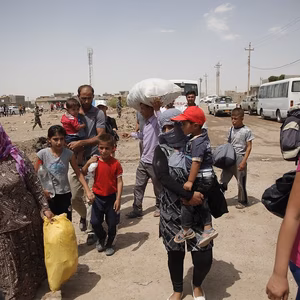 Relief effort for Syrian refugees in a refugee camp in Northern Iraq. Various families carry their possessions on a dirt road