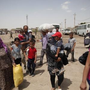 Relief effort for Syrian refugees in a refugee camp in Northern Iraq. Various families carry their possessions on a dirt road