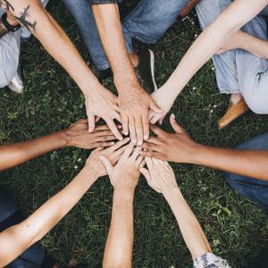 Many different peoples hands join in the centre of a circle