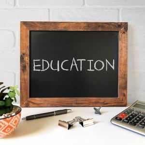 Black chalkboard displaying the words 'education' with a calculator, pens, and other smll objects placed infront