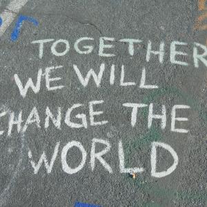White chalk writing on the floor that says ' Together we will change the world'