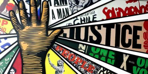 Cartoon style graphic of a raised hand, many words related to social just are coming out from the hand in different colours