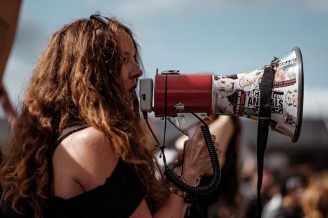 Young woman with wavy auburn hair hold a megaphone upto her mouth