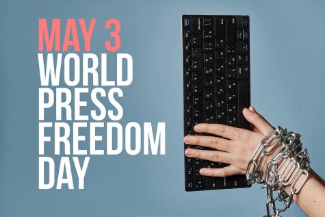 Black keyboard with a chained white hand on top of it with a blue background | World Press Freedom Day is written on the left side in large pink and white letters