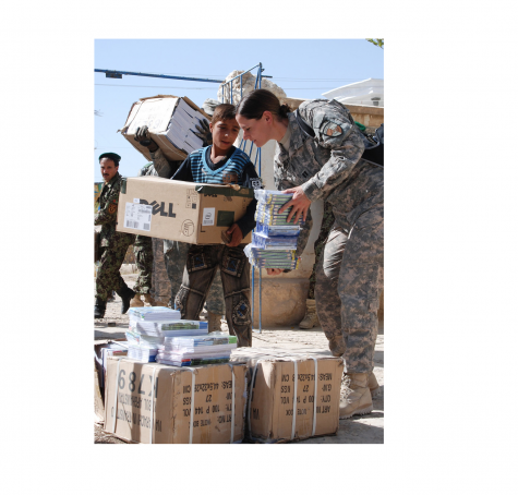 Female US Army worker hands boxes of school supplies over to a student