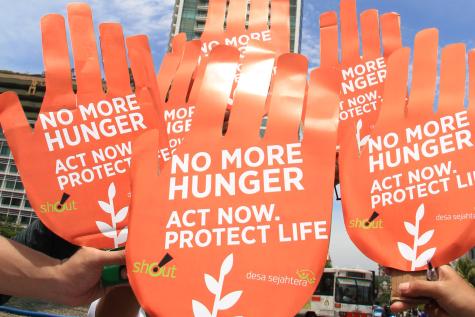 Six giant orange hands are held in the air display the words 'No more hunger. Act now'