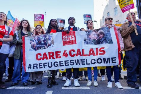 Activists hold a white and 'Care4Calais' banner during a march against racism in central London in support of refugees