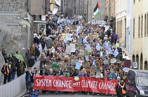 Campaigners in November 2022 marched through Edinburgh as part of Global Day of Action for climate justice during the UN Climate Conference COP27 in Egypt. At the front of the protest there is a large red banner which reads 'System change not climate change.'