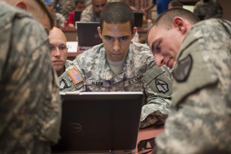 Four U.S. cyber specialist soldiers look intently at a laptop screen
