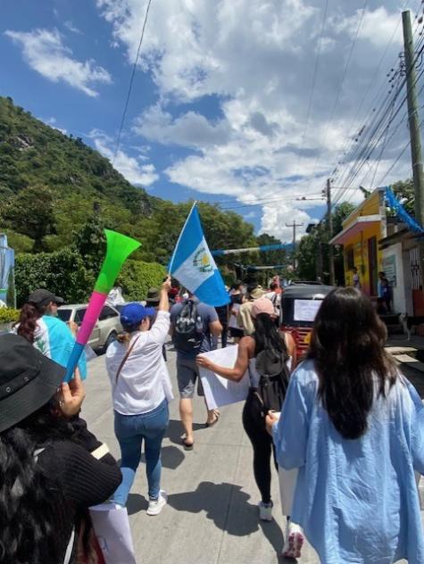 Many prodemocracy protesters march the streets in Guatamala holding flags and signs 