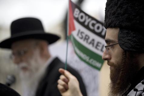 Close up image of two Jewish men at a pro-Palestine protest. One is holding a Palestinian flag
