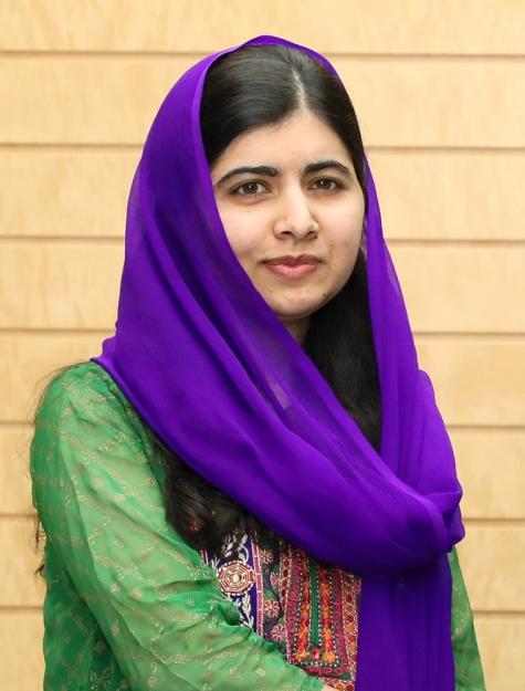 Image of Pakistani girls education activist Malala Yousafzai. She is looking directly into the camera and wears a purple headscarf with a green sari