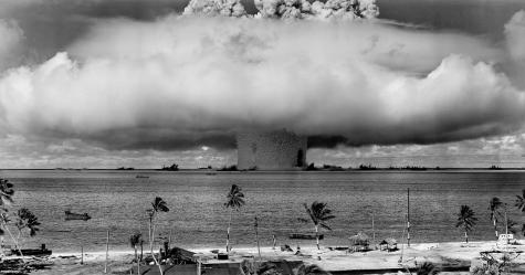 Black and white image of a huge mushroom cloud over the ocean formed after a nuclear explosion