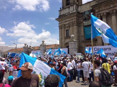 Many protesters gather in Guatemala city holding large blue and white flags