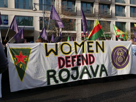 A banner explaining the importance and role of women in the defense of Rojava