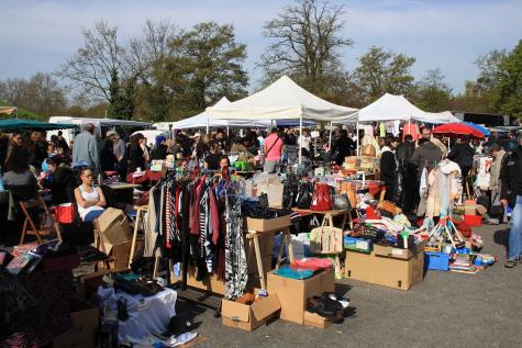 A second-hand market in Champigny-sur-Marne, France where lots of white gazeebos cover many tables and clothing rails all filled with used items ready to sell
