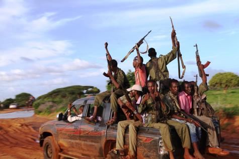 Juba forces drive away in a pickup truck celebrating rescuing hostages.  8 men wearing uniforms sit in the back of the truck holding their guns high.