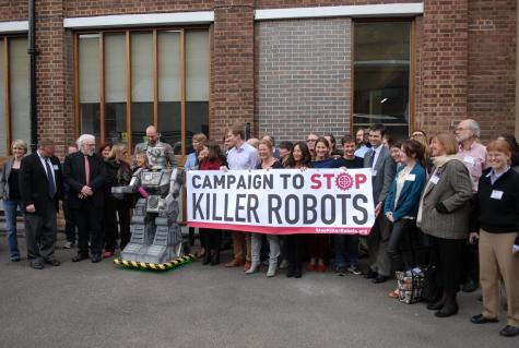 Protesters stand infront of a building holding a sign that says 'Campaign to stop killer robots'.