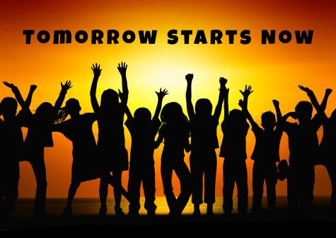 The silhouettes of many children standing in a line are infront of a sunset background. The words 'Tomorrow starts now' are written above them in black