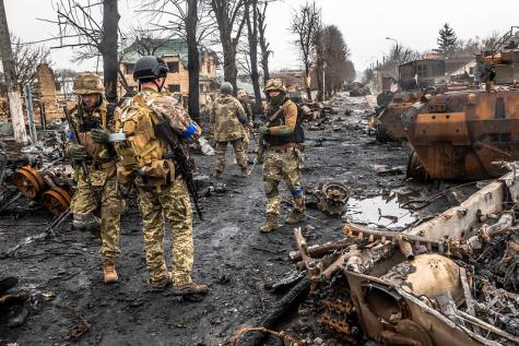 Ukrainian soldiers inspecting the charred remains of a Russian military convoy in Bucha