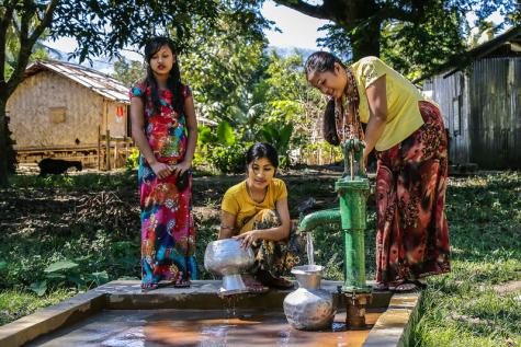 Three women in Banglashdesh collect water from a pump in Banderban.