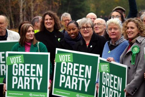 Several Green Party supporters gather holding large green signs which say 'Vote Green Party'