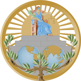 International Court of Justice Seal - A figure in a blue tunic sits on a grand chair holding a balance. Below is two images of different sides of the Earth. It is suurrounded by a golden circle and many green leaves