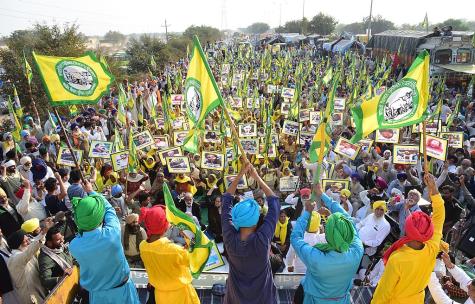 Thousands of people line the streets at the 2020 Indian farmers' protest. Yellow and green flags are held high in the air