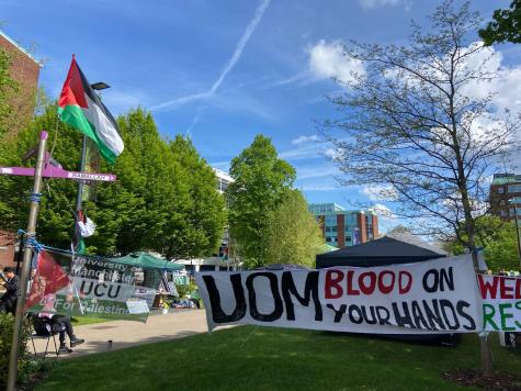 Banners hang at the entrance to the University of Manchester Gaza protest encampment. The signs read &lsquo;UOM blood on your hands&rsquo; and &lsquo;University of Manchester UCU for Palestine&rsquo;. 