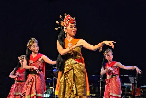 Four Malaysian women in traditional dress dance on stage 