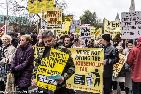People line the streets at an anti-austerity protest in Dublin, many are carrying signs against the household tax and budget cuts.