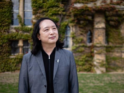 2025 Right Livelihood laureate Audrey Tang stands in a courtyard infront of a beautiful building overgrown with leaves.
