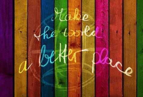 Colourful painted boards of wood have the words 'Make the world a better place' written on them in white chalk
